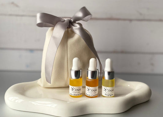 3 mini testers, 3ml dropper bottles filled with our 3 signature oils on a white tray next to a soft white velvet pouch with a silver ribbon