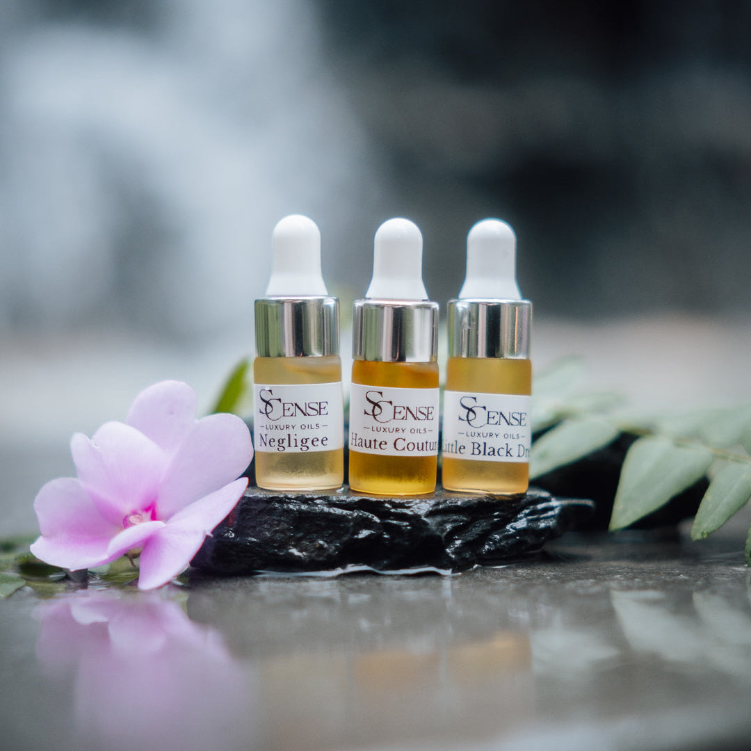Three trial size skincare serum bottles labeled 'Sense' with a pink flower on a dark surface.