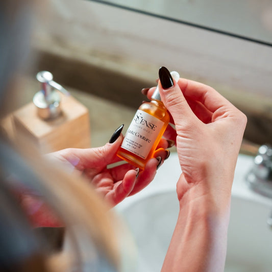 Person holding a bottle of Haute Couture Face oil in a bathroom setting