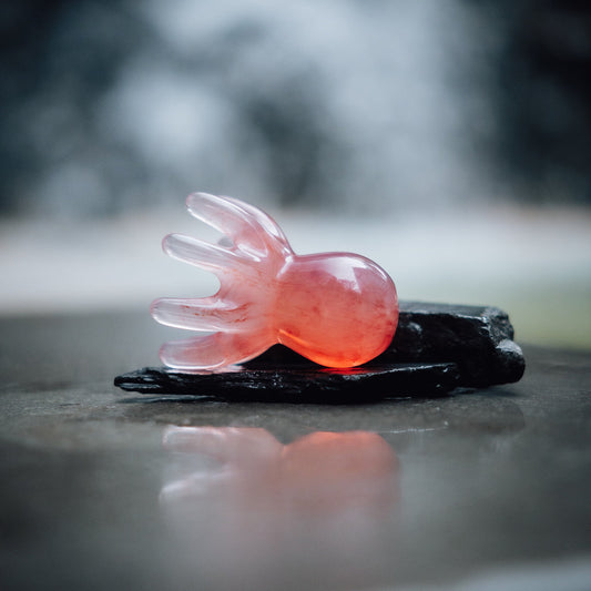 Pink octopus shaped scalp massager on a dark stone surface with a blurred natural background